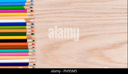 Colorful pencils lined up on oak wooden desktop Stock Photo
