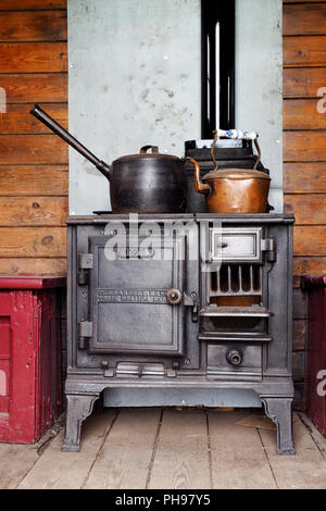 A small Victorian cast iron cooking range provides heat and cooking facilities in an English shepherd's hut. Stock Photo