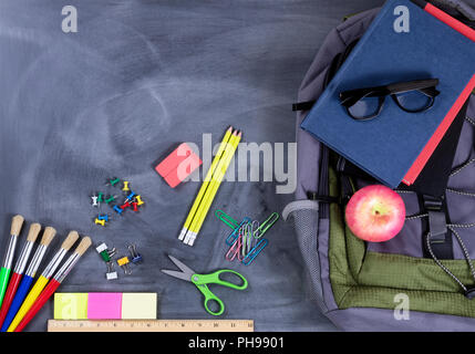 Back to school supplies and backpack on chalkboard background Stock Photo