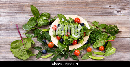 Healthy fresh salad in bamboo plate on rustic wooden boards Stock Photo