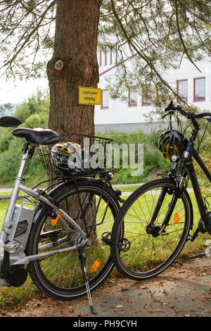 Precious bicycles and helmets are parked in a park ban Stock Photo