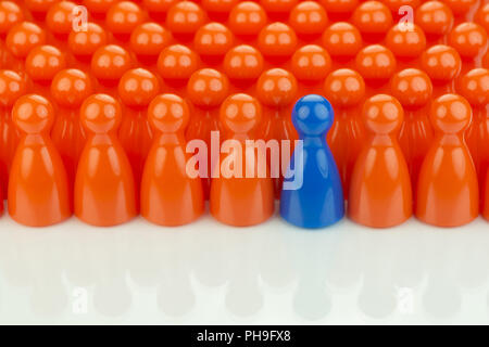 Conceptual orange game pawns and a blue game pawn Stock Photo