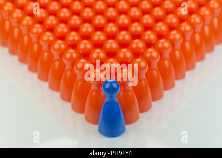 Conceptual orange game pawns and a blue play pawn Stock Photo