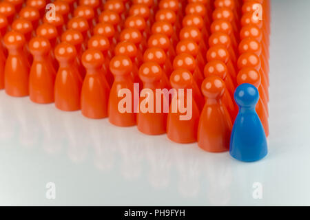 Conceptual orange game pawns and a blue play pawn Stock Photo