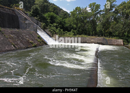 Dam wall and overflow of Iskar Dam. Water flowing over a dam wall. Mist rising above the Iskar dam wall. Cascade from a hydroelectric plant. Lake wate Stock Photo