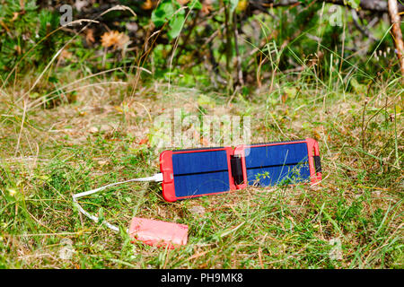 Portable solar panel charges the battery of a powerbank - an alternative energy source in the wild concept Stock Photo