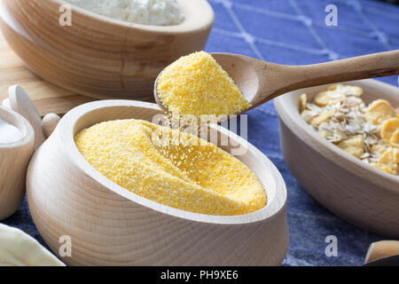 Female hand picking up corn flour with wooden spoon Stock Photo