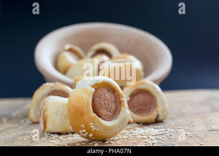 Sausages rolled in croissant dough baked cooling on metal rack. Stock Photo