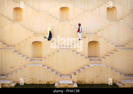 A Hindu man and woman dressed in traditional clothing, walk down the maze steps of Panna Meena ka Kund Stepwell, Amer, Rajasthan, India, Asia Stock Photo