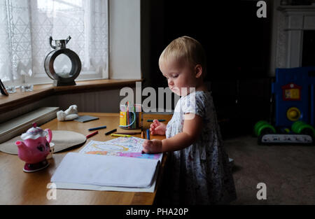 Young female girl child at 20 months old enjoying herself drawing with crayons Stock Photo