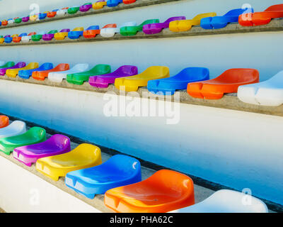 Several rows of colorful seats in a stadion during day time Stock Photo