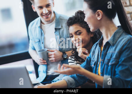 Optimistic three students collaborating on project Stock Photo