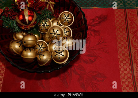 bowl full of gold jingle bells on a red tablecloth Stock Photo
