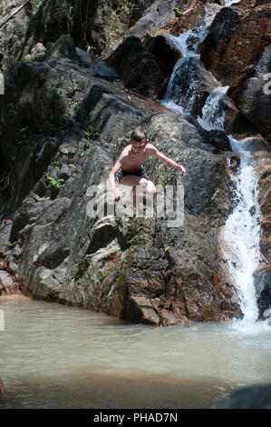 Child jumping in waterfall Stock Photo