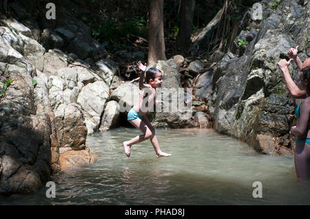 Child jumping in waterfall Stock Photo