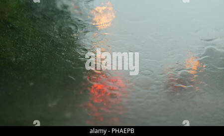 Road view through car window with rain drops, Driving in rain. Window's car while heavy rain. Stock Photo