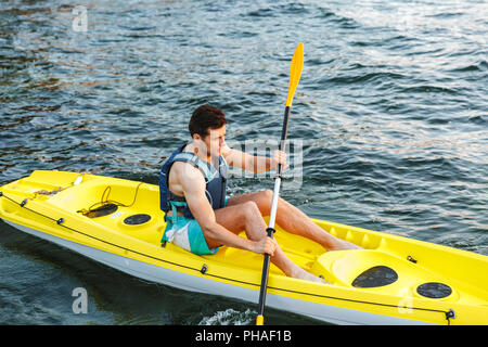 Young man kayaking on a lake. Happy young man canoeing in a lake Stock Photo
