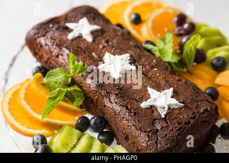 Chocolate brownie cake with fresh blueberry, white sugar stars and oranges. Homemade chocolate cake served with fruit. Stock Photo