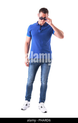 Young man holding sunglasses with over the glasses look at camera. Full body isolated on white background. Stock Photo