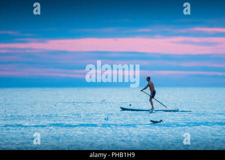 Aberystwyth Wales UK, Friday 31 August 2018  UK Weather: On the last day of meteorological summer (August 31st) , a man paddles on his stand up board on the calm waters of Cardigan Bay, off Aberystwyth, as the sky reddens behind him at dusk  photo © Keith Morris / Alamy Live News Stock Photo
