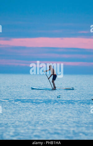 Aberystwyth Wales UK, Friday 31 August 2018  UK Weather: On the last day of meteorological summer (August 31st) , a man paddles on his stand up board on the calm waters of Cardigan Bay, off Aberystwyth, as the sky reddens behind him at dusk  photo © Keith Morris / Alamy Live News Stock Photo