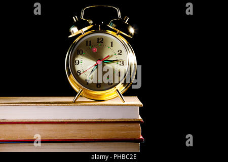 alarm clock standing on books Stock Photo