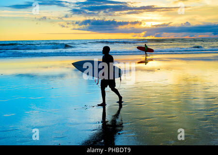 Surfers walking on the beach Stock Photo