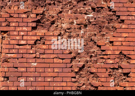 old damaged by bullets and shells brick red wall of the ancient fortification Stock Photo