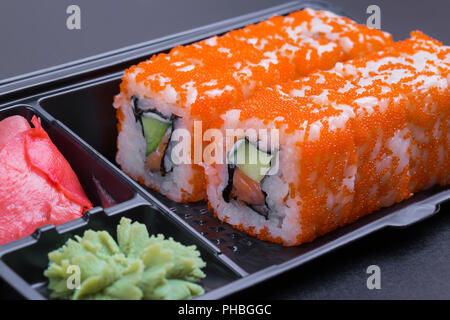 Set of California rolls in a black 'take away' container on a black background side view Stock Photo