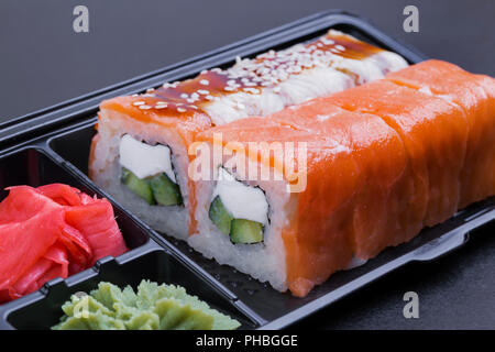Set of mix rolls of Philadelphia and eel in a black container 'take it away' on a black background side view Stock Photo