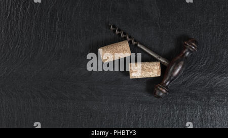 Overhead view of vintage corkscrew on black slate background Stock Photo