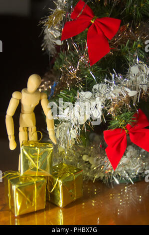 Mannequin next to the Christmas tree and golden boxes of gifts for Christmas Stock Photo