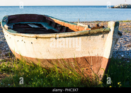 Old boat on the seashore covered with grass Stock Photo