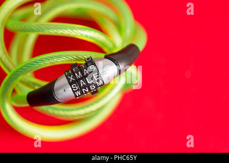 Plastic covered bike cable and combination lock with the code - Xmas Sale - over a festive red background with copy space for seasonal promotions and  Stock Photo
