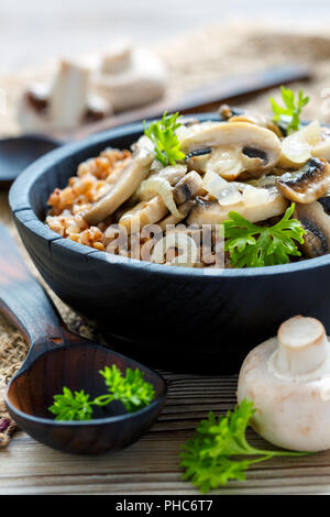 Buckwheat porridge with mushrooms in a wooden bowl. Stock Photo