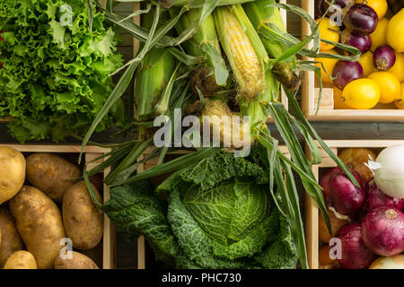 Assortment of healthy fresh raw vegetables and fruit in a wooden boxes at an organic farmers market viewed close up from above in a full frame food ba Stock Photo