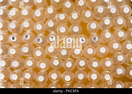 Multiple clean plastic bottles for recycling to save the environment viewed from overhead with the word - Recycle - handwritten on the white caps in a Stock Photo