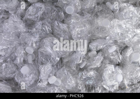 Background texture of crumpled crushed clear plastic bottles piled in a heap ready for recycling to save the environment Stock Photo