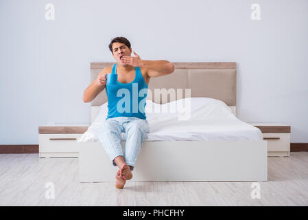 Young man waking up in bed Stock Photo
