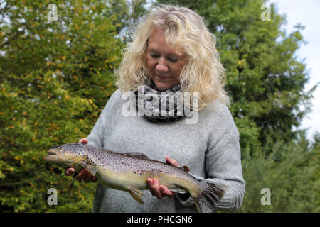 Woman presents a brown trout, Salmo trutta fario Stock Photo