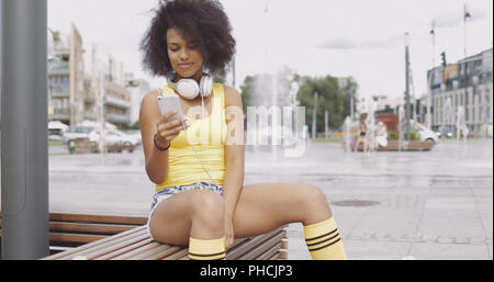 Sportive girl using smartphone on bench Stock Photo