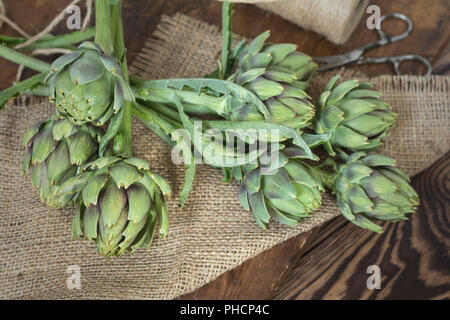Two artichoke bouquets on sackcloth on wooden background. Top view. Stock Photo
