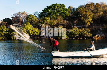 Cuban fishermen catch seafood using traditional method of casting hand net into the ocean from rowboat. Stock Photo