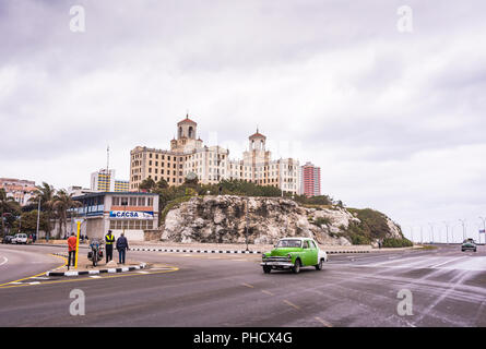 Havana, Cuba / March 21, 2016: Vintage green car on the Malecon highway in front of  historic National Hotel. Stock Photo
