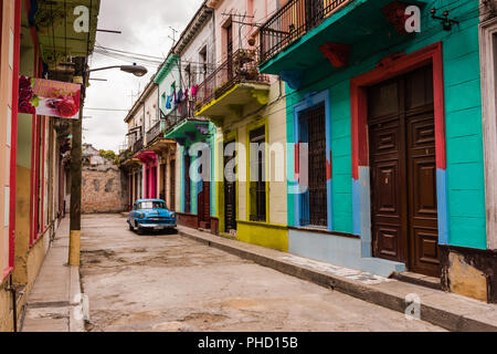 Havana, Cuba / March 22, 2016: Brightly painted facades of Colonial era buildings with second story wrought iron balconies in an alley of Old Havana.  Stock Photo