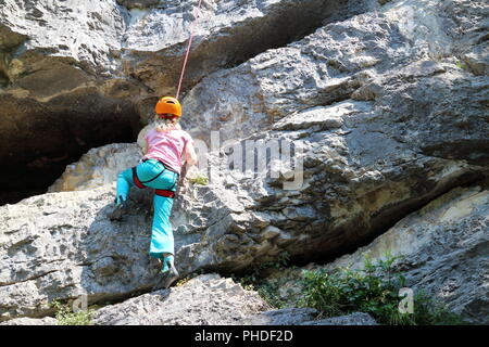 girl is climbing on rock wall Stock Photo
