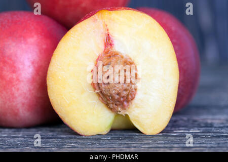 several bright red nectarines, one of which is cut into half, closeup Stock Photo