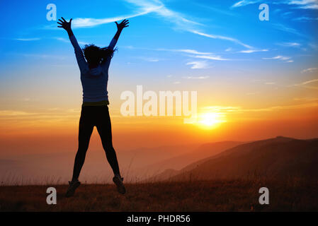 Silhouette of happy jumping young woman Stock Photo