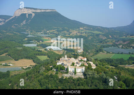 AERIAL VIEW. Perched medieval village surrounded by orchards, Mount Saint-Genis in the distance. Ventavon, Hautes-Alpes, Provence, France. Stock Photo