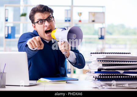 Angry aggressive businessman with bullhorn loudspeaker in office Stock Photo
